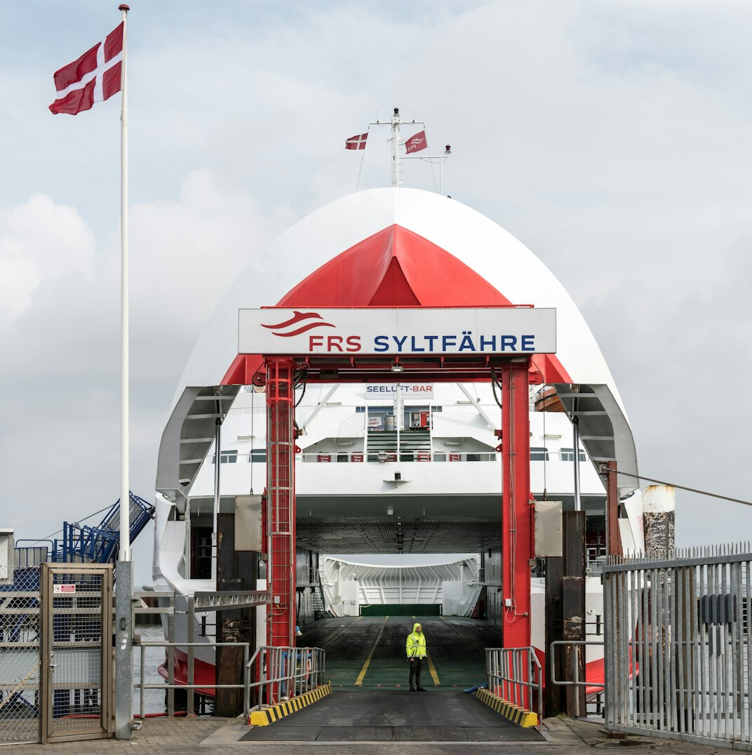 Travelers waiting in line at a Danish ferry terminal with cars and bicycles