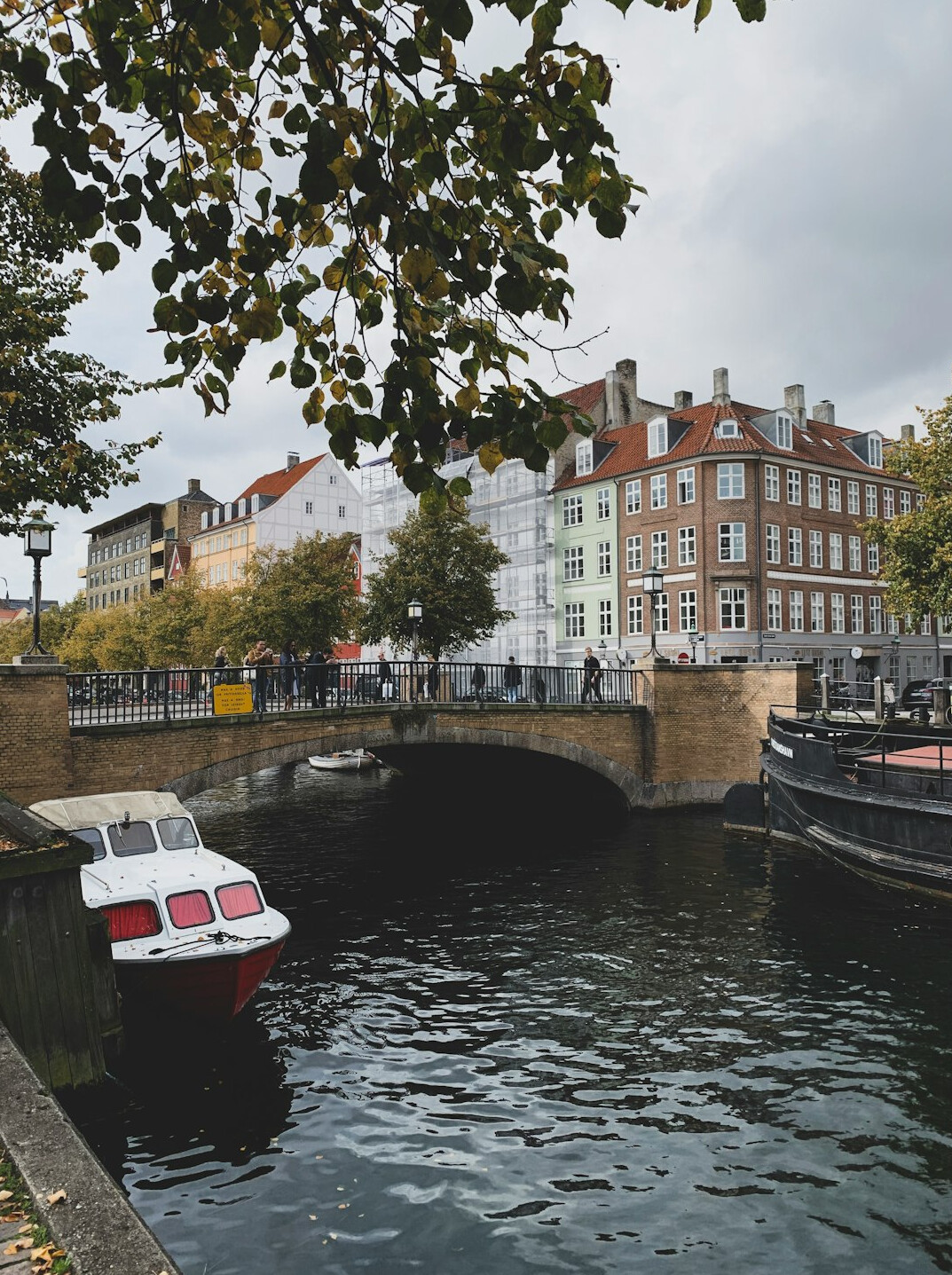 Colorful townhouses along a Copenhagen canal with people walking by